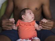 In this Dec. 23, 2015 photo, Dejailson Arruda holds his daughter, Luiza, at their house in Santa Cruz do Capibaribe, in Pernambu